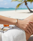 Pulsera ClaraJoyas de hilo mostaza ajustable con perla central y cuentas de amazonita en una playa tropical