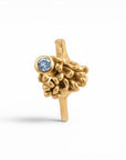 Sophia Schneider Joyas 18K gold ring with a small blue tanzanite gemstone and organic, textured detailing.