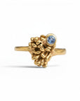 Sophia Schneider Joyas 18K gold ring with a textured, organic design and a small round blue tanzanite gemstone.