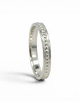 Anillo cintillo de plata 925 de Sophia Schneider Joyas con diseño de pelotitas y detalles grabados.