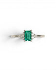Anillo Sophia Schneider Joyas de platino con esmeralda rectangular central y diamantes laterales.