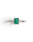 Anillo Sophia Schneider Joyas de platino con esmeralda rectangular central y diamantes laterales.