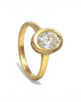 Sophia Schneider Joyas 18K yellow gold ring with 1 ct oval lab-grown diamond, bezel set with small accent diamonds.