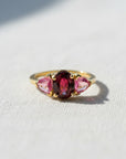 Anillo Sophia Schneider Joyas de oro 18K con rubelita oval central y zafiros rosados triangulares laterales.