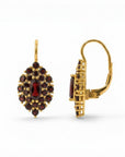 Sophia Schneider Joyas 14K gold dangle earrings featuring a marquise-cut garnet center surrounded by smaller round garnets in a floral cluster design.