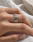Anillo banda ajustable de 7 mm en plata con textura rugosa y bordes lisos de Sophia Schneider Joyas en una mano