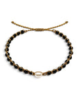 Pulsera ajustable ClaraJoyas con hilo dorado, cuentas de ónix negro y una perla central blanca