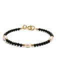 Pulsera ClaraJoyas de cuentas de onix negro facetado con tres perlas blancas y detalles dorados, ajustable de 16 cm.