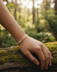 Pulsera ajustable ClaraJoyas con perlas naturales y barra de goldfilled sobre un tronco cubierto de musgo