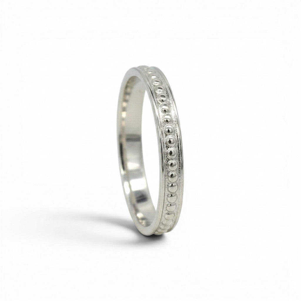 Anillo cintillo de plata 925 de Sophia Schneider Joyas con diseño de pelotitas y detalles grabados.