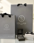 Anillo solitario de diamante corte esmeralda Sophia Schneider Joyas en estuche junto a bolsas de regalo grises