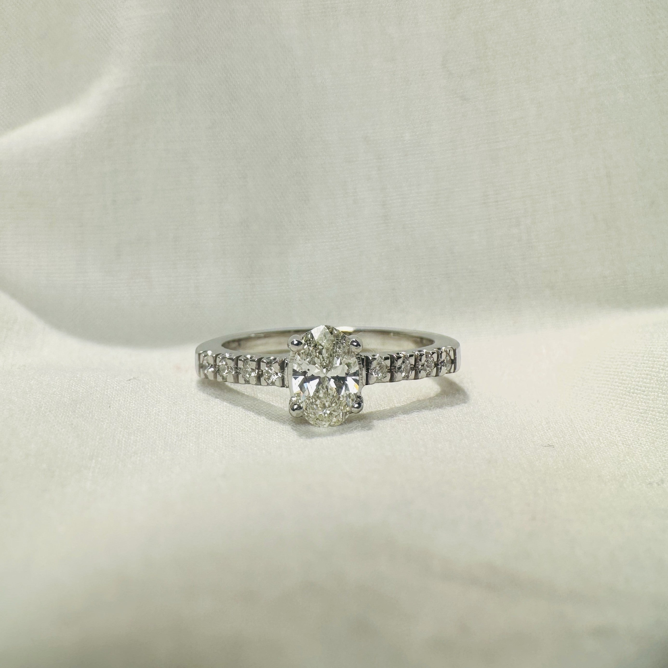 Anillo solitario de platino Sophia Schneider Joyas con diamante central oval de 0,6 ct y diamantes en la argolla.