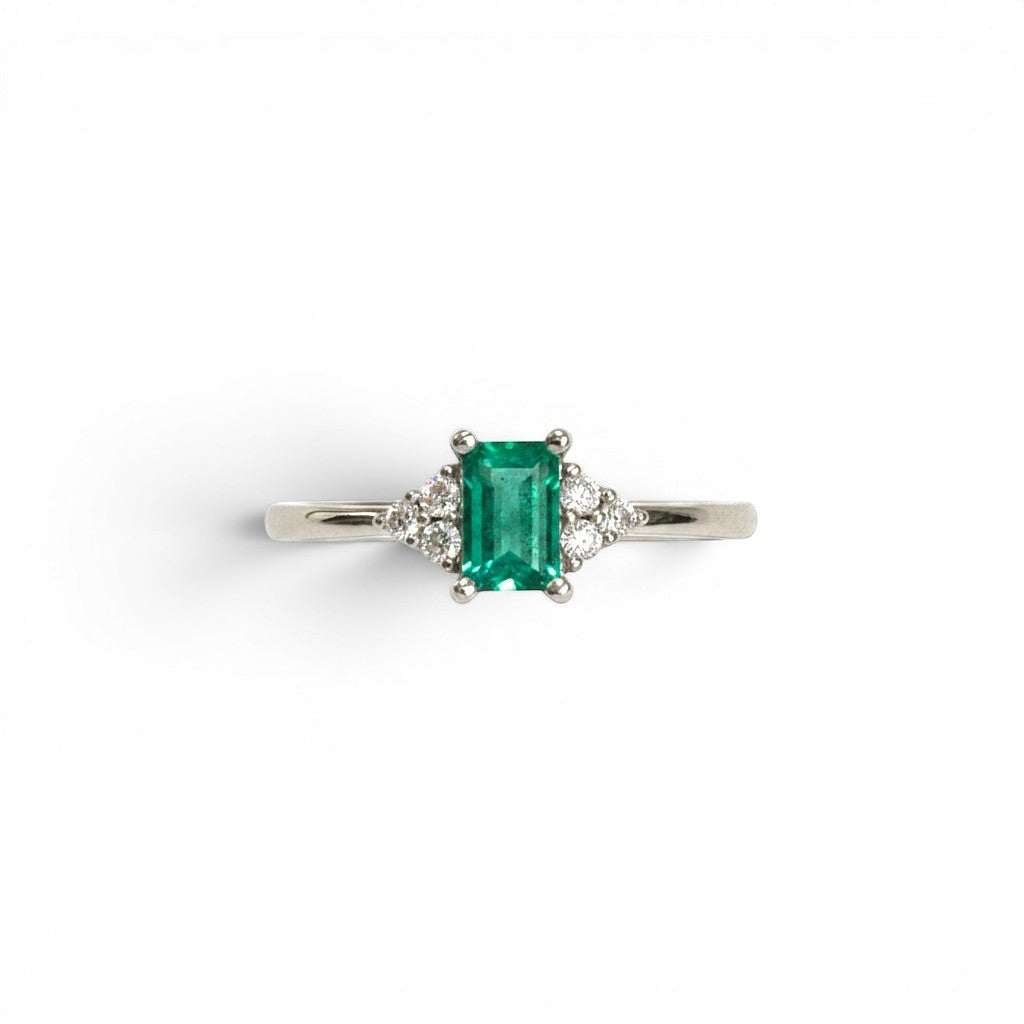 Anillo Sophia Schneider Joyas de platino con esmeralda rectangular central y diamantes laterales.