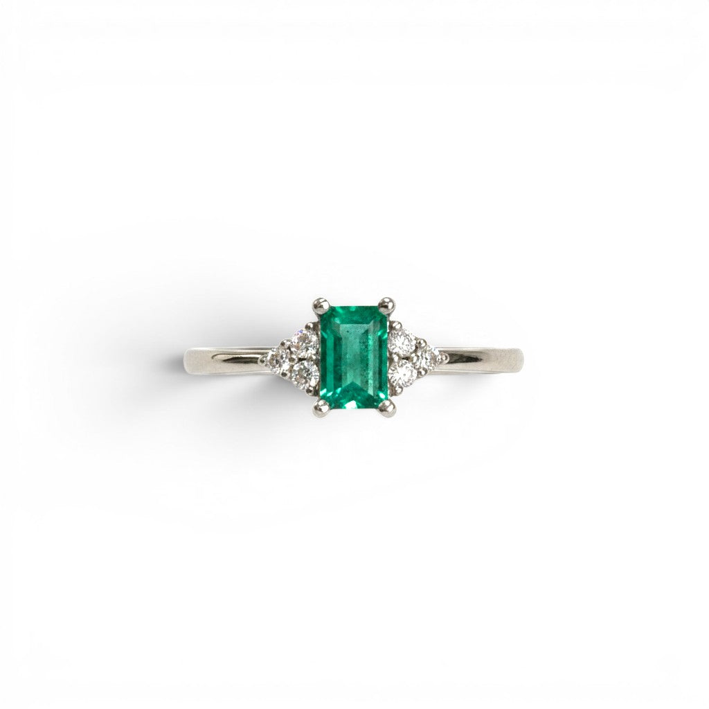 Anillo Sophia Schneider Joyas de platino con esmeralda rectangular central y diamantes laterales.