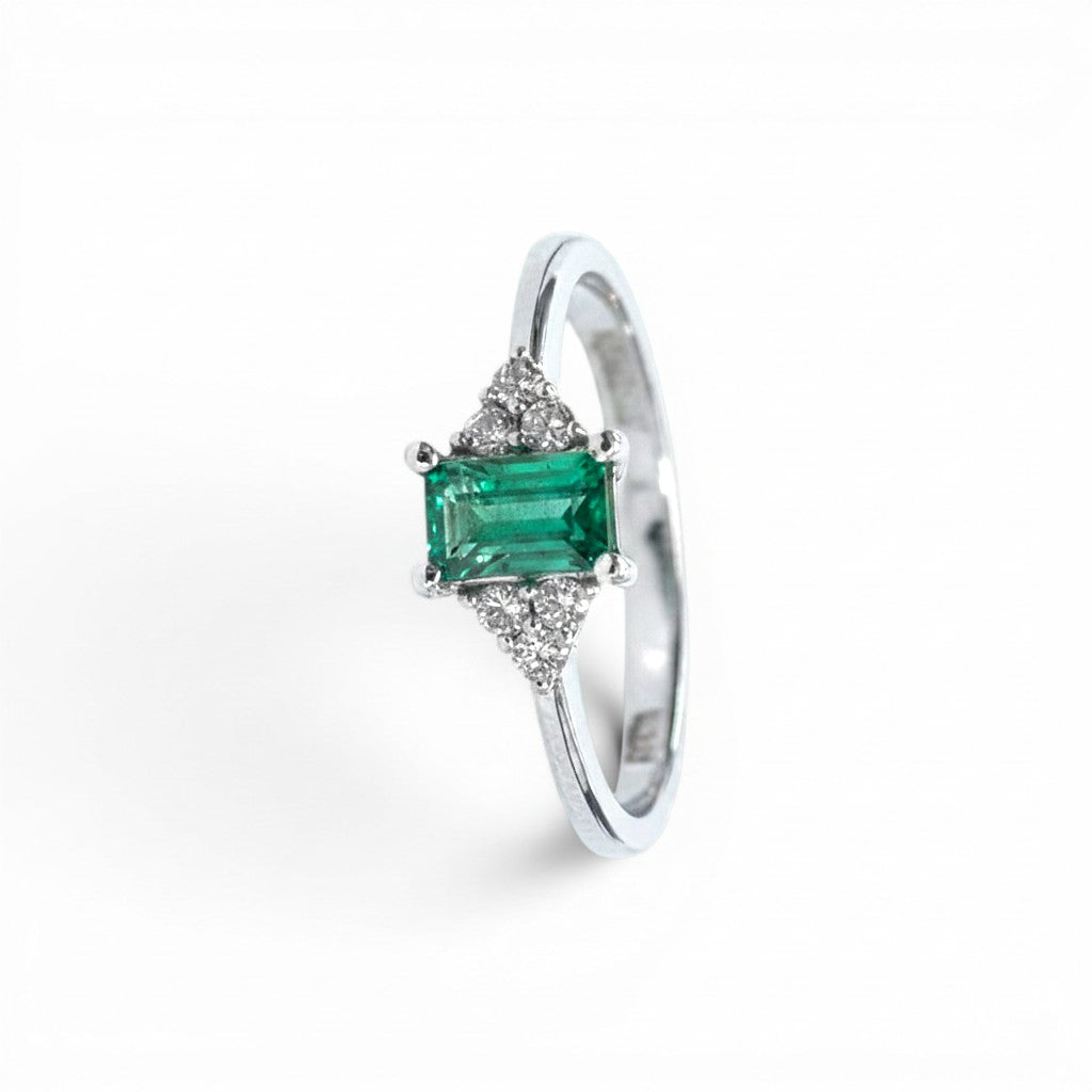 Anillo Sophia Schneider Joyas de platino con esmeralda rectangular central y diamantes laterales.