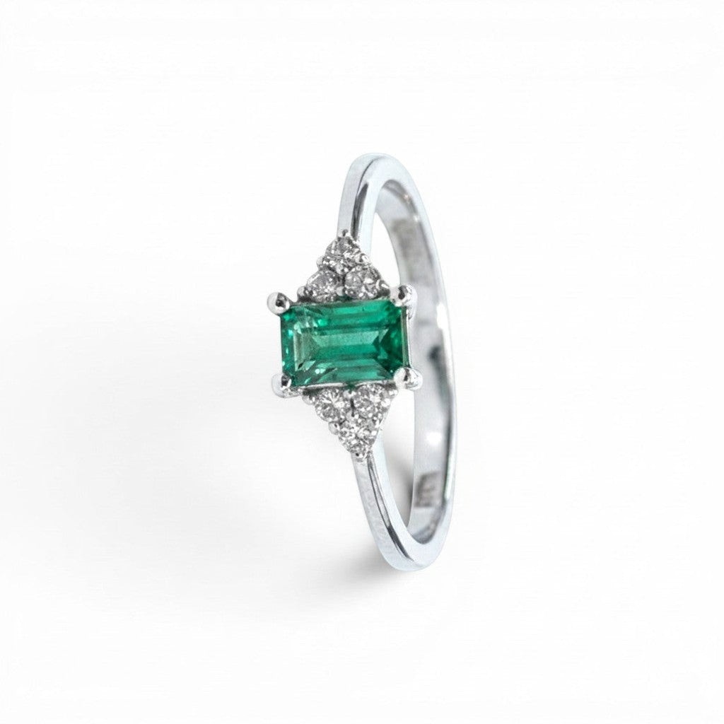 Anillo Sophia Schneider Joyas de platino con esmeralda rectangular central y diamantes laterales.