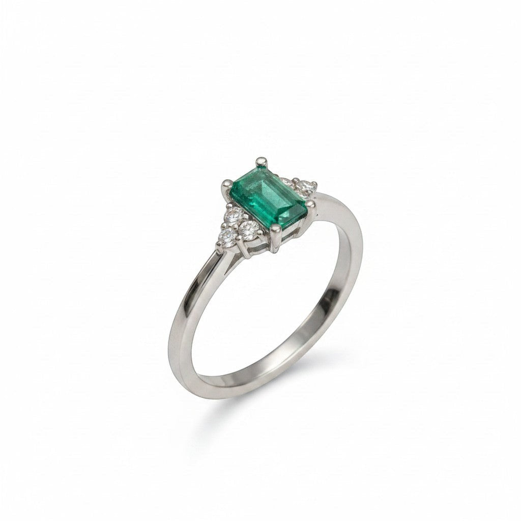 Anillo solitario de platino Sophia Schneider Joyas con esmeralda rectangular central y tres diamantes a cada lado.
