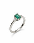 Anillo solitario de platino Sophia Schneider Joyas con esmeralda rectangular central y tres diamantes a cada lado.