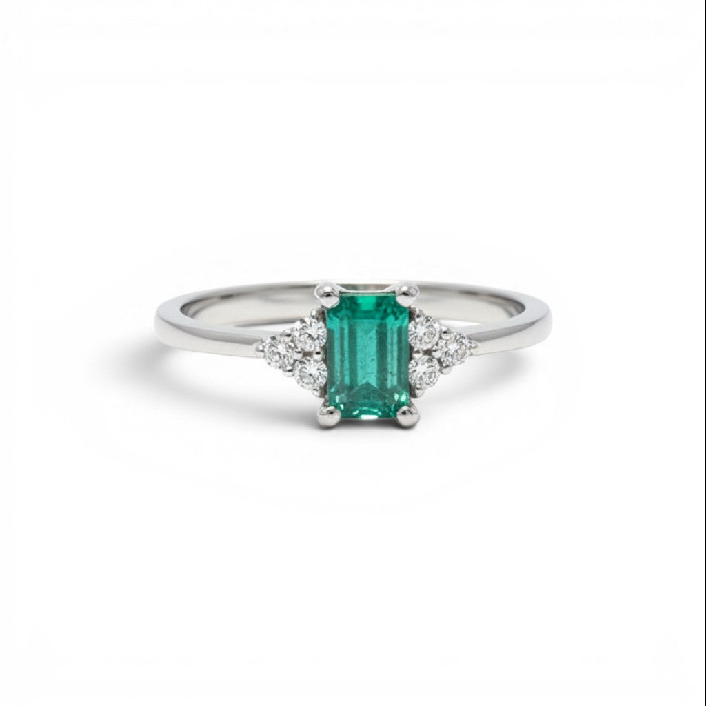 Anillo solitario de platino Sophia Schneider Joyas con esmeralda rectangular verde y diamantes laterales.