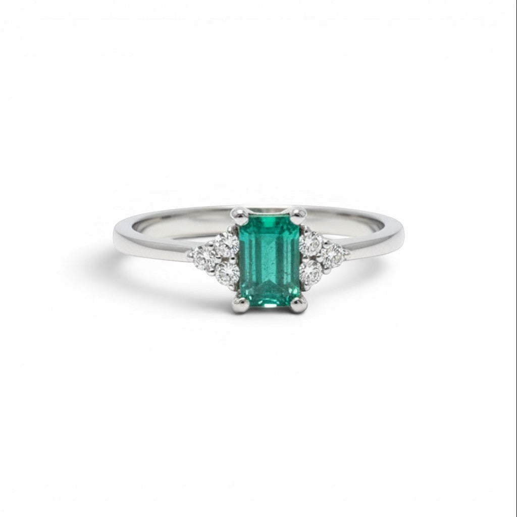Anillo solitario de platino Sophia Schneider Joyas con esmeralda rectangular verde y diamantes laterales.
