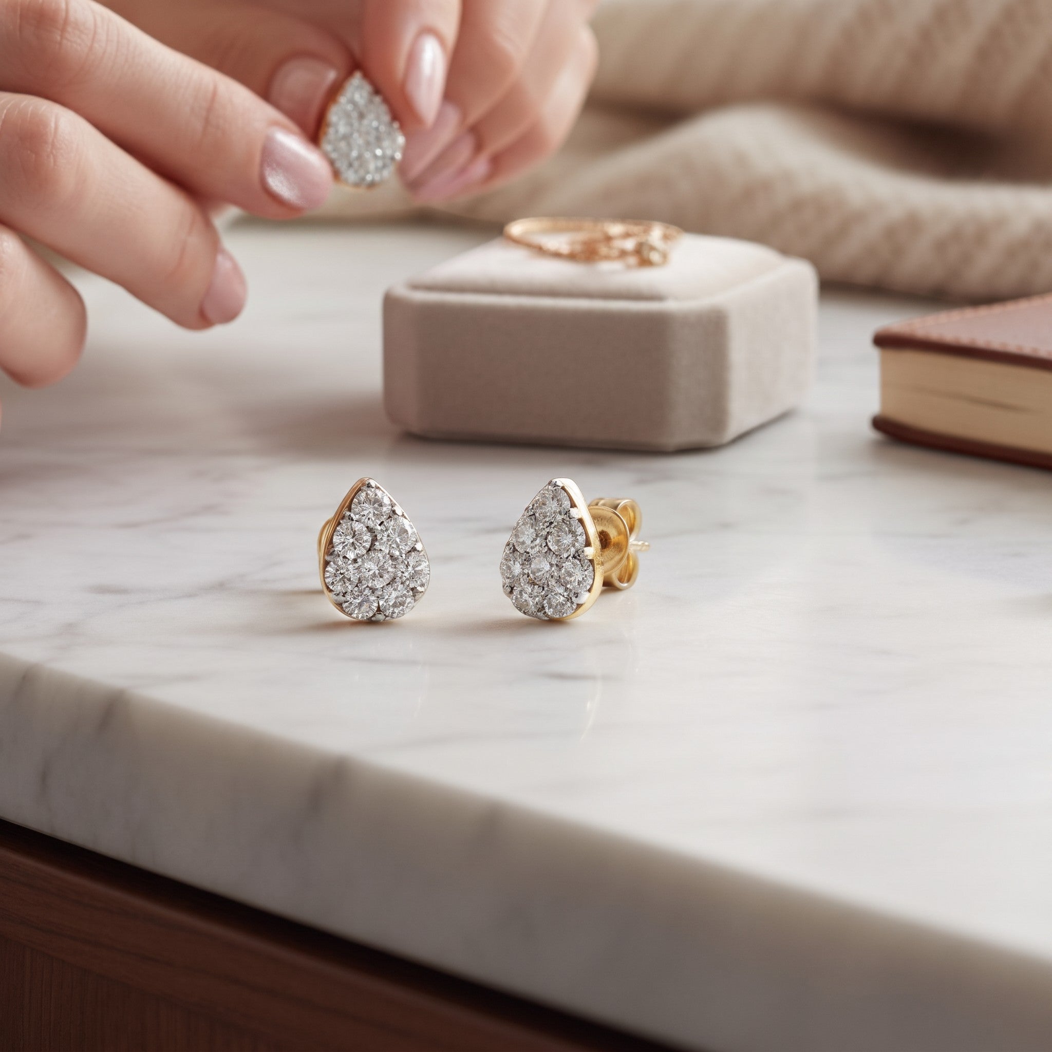 Aros stud Sophia Schneider Joyas en forma de gota de oro blanco 10K con diamantes pavé de 0,20 ct sobre mesa de mármol