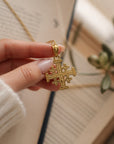 Colgante de Cruz de Jerusalén en oro de 14K sostenido por una mano, de la colección Sophia Schneider Joyas.
