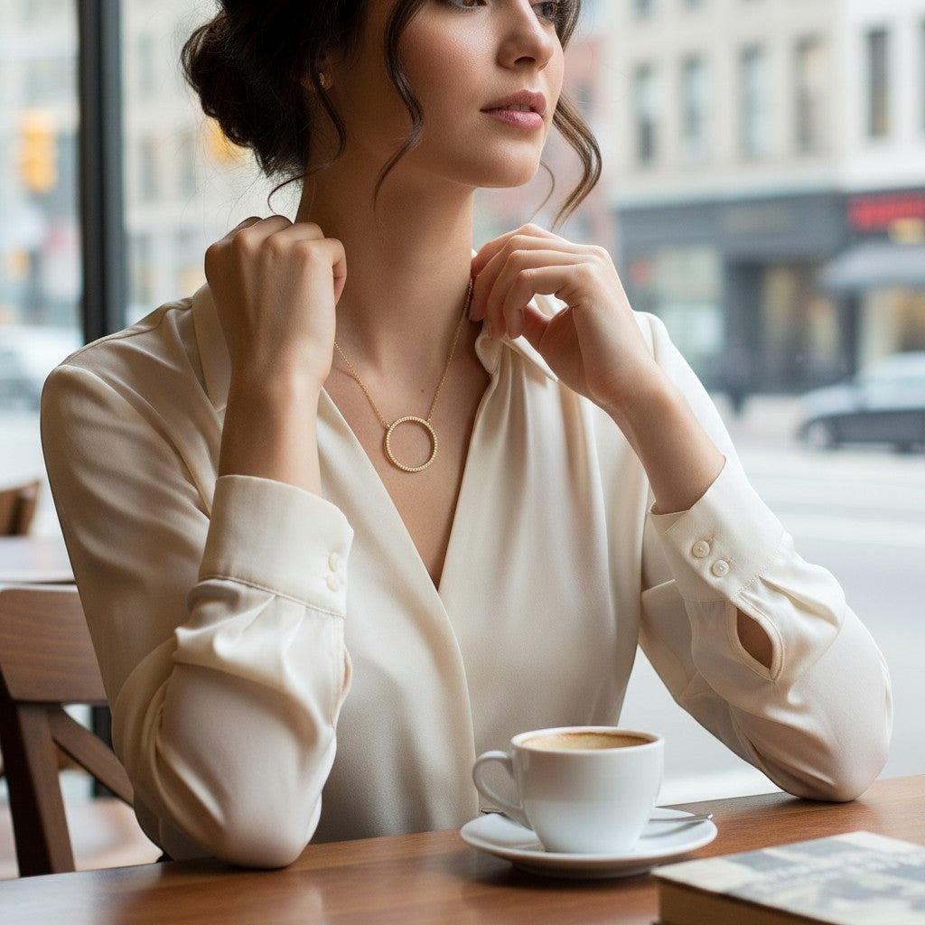 Collar Sophia Schneider Joyas con círculo de diamantes y cadena de oro 18K lucido por una mujer en una cafetería