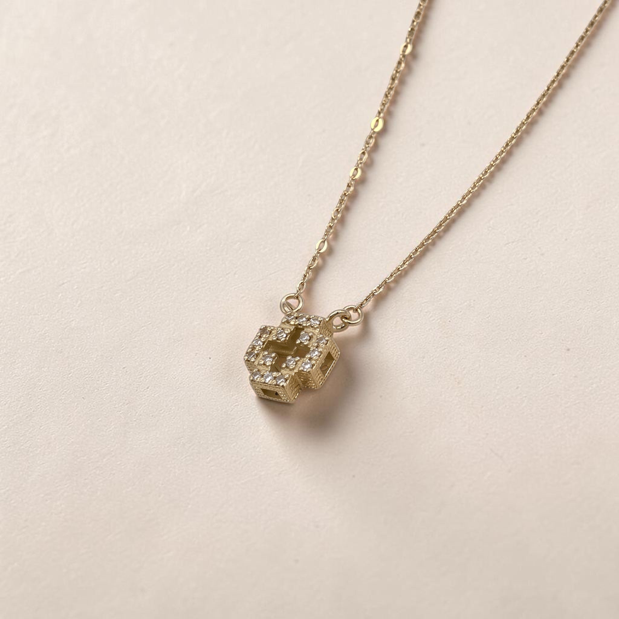 Collar Sophia Schneider Joyas con cruz tridimensional de oro 18K y diamantes brillantes sobre fondo neutro