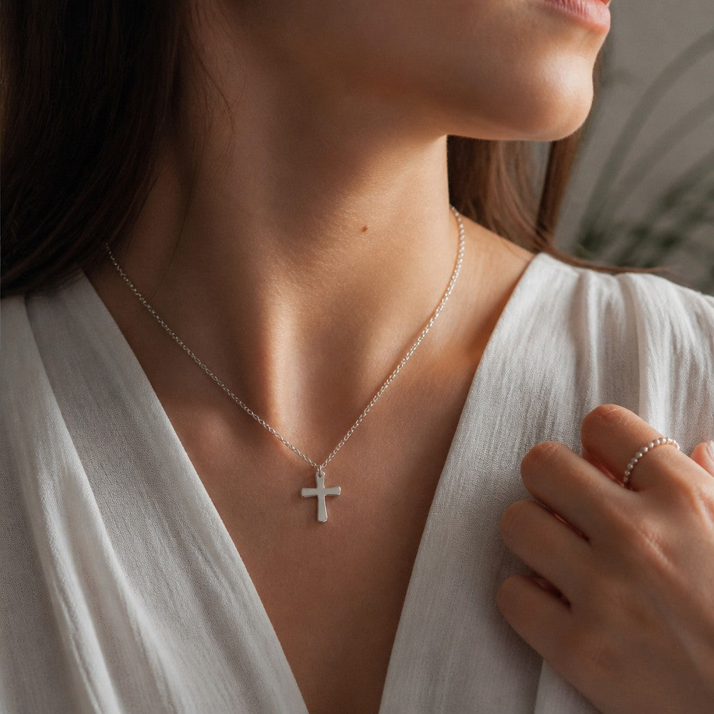 Collar con cruz pequeña de plata 925 con baño de rodio de Sophia Schneider Joyas sobre modelo con blusa blanca