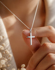 Cruz de Sophia Schneider Joyas en plata 925 de 9x15 mm sostenida por una mano con delicadeza