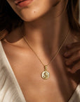 Medalla redonda de la Virgen orando en oro de 18K con cristal, de la marca Sophia Schneider Joyas, puesta en el cuello.