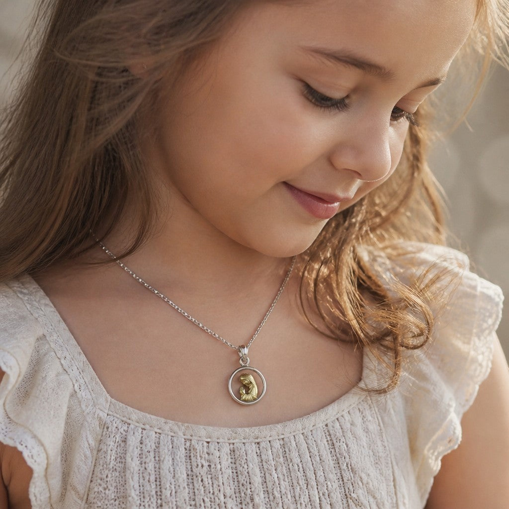 Niña luciendo medalla redonda de Sophia Schneider Joyas con Virgen orando en plata y oro laminado de 12 mm