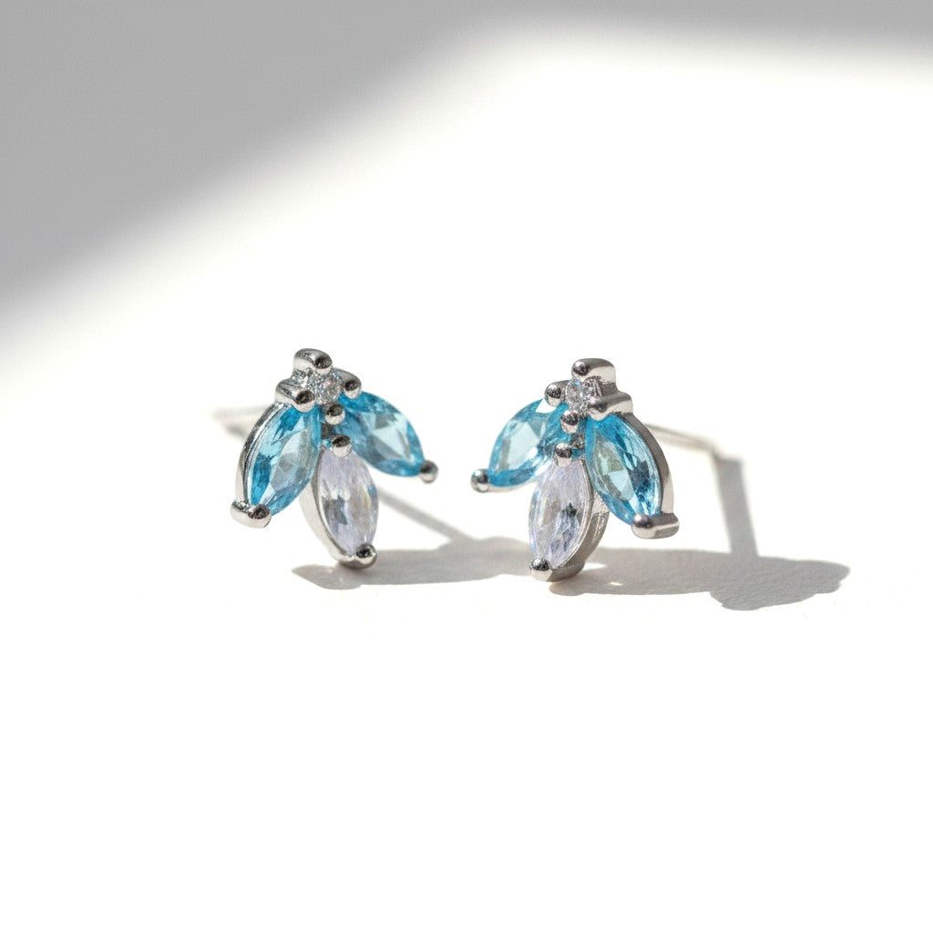 Sophia Schneider Joyas 14K gold earrings with marquise-cut blue topaz and white cz stones, delicate floral design.