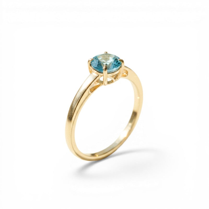 Sophia Schneider Joyas 18K gold ring with a round, blue topaz gemstone. Classic solitaire design.