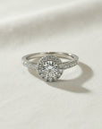 Anillo de platino Sophia Schneider Joyas con diamante central brillante de 0,50 ct y halo de diamantes pequeños, engastado en grifa.