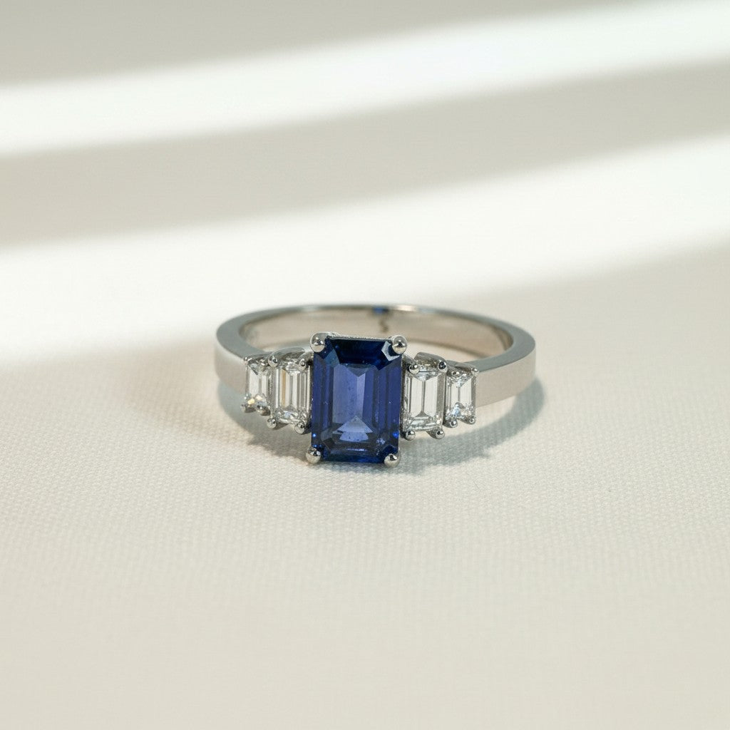Anillo de platino Sophia Schneider Joyas con zafiro octogonal azul central y diamantes baguette laterales.