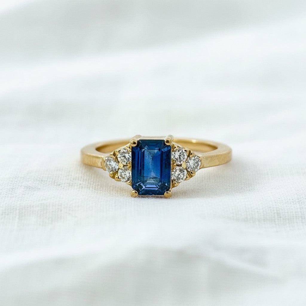 Anillo Sophia Schneider Joyas de oro amarillo 18K con zafiro central octogonal azul y diamantes corte brillante a cada lado.