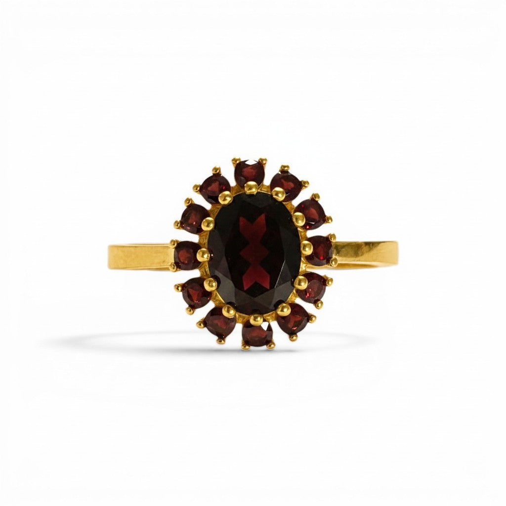 Sophia Schneider Joyas 14K gold ring with oval garnet center stone surrounded by smaller garnets in a floral halo design.
