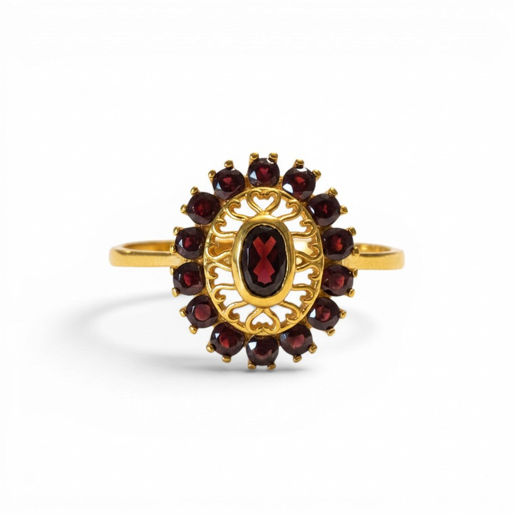 Sophia Schneider Joyas 14K gold ring with oval garnet center stone surrounded by a halo of smaller garnets in a floral design.