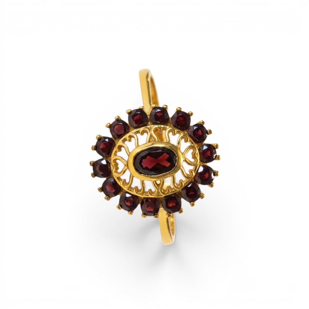 Sophia Schneider Joyas 14K gold ring with oval garnet center stone and halo of smaller garnets in a floral design.