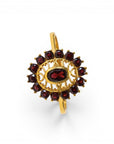 Sophia Schneider Joyas 14K gold ring with oval garnet center stone and halo of smaller garnets in a floral design.