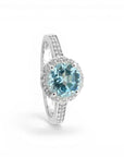 Sophia Schneider Joyas sterling silver ring with a round 2 ct blue topaz center stone surrounded by small clear stones.
