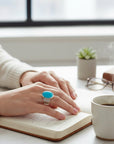 Sophia Schneider Joyas sterling silver ring with a large oval turquoise stone and multiple band details.